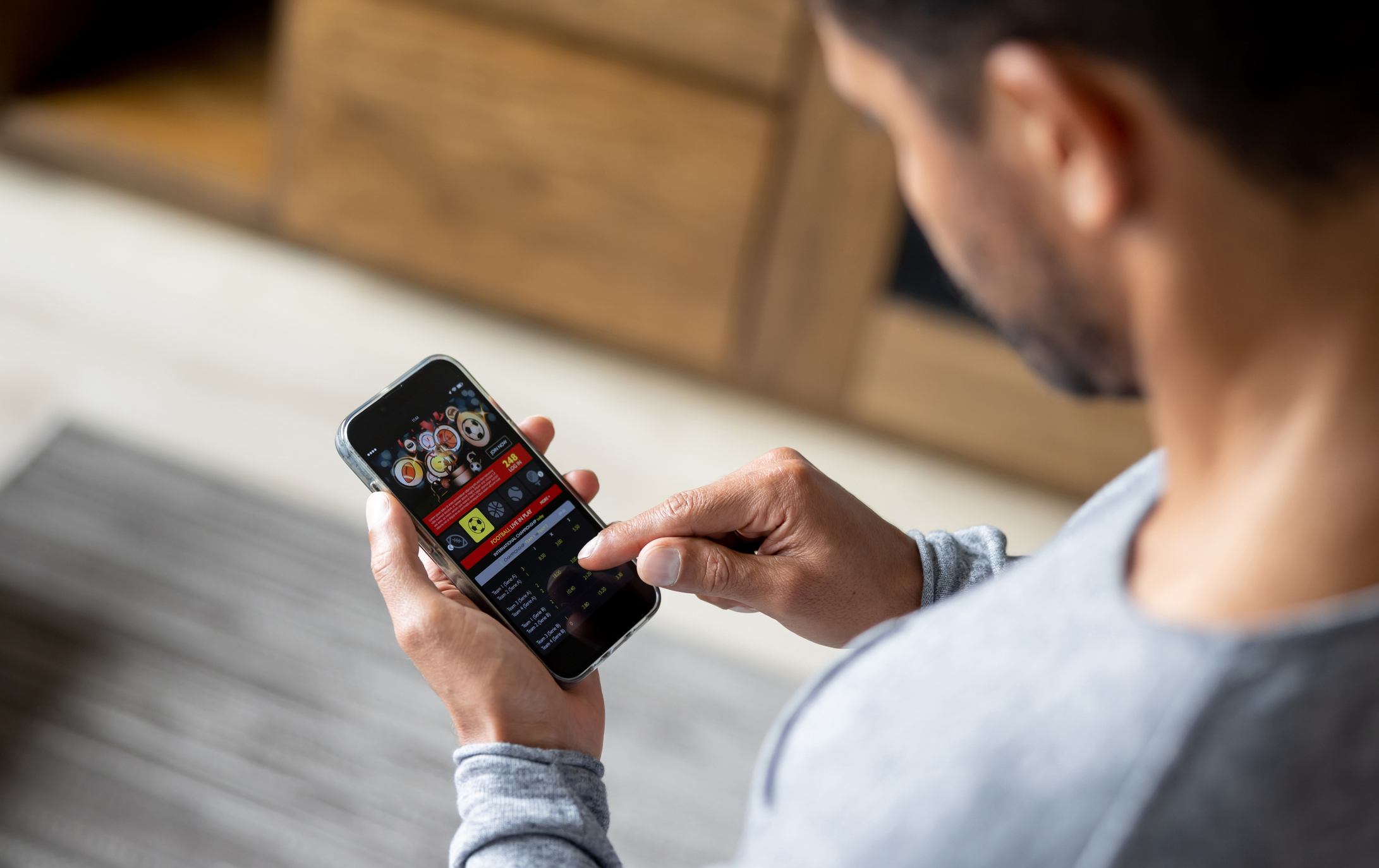Ein Mann schaut auf sein Handy, auf dem eine Spiele-App geöffnet ist.