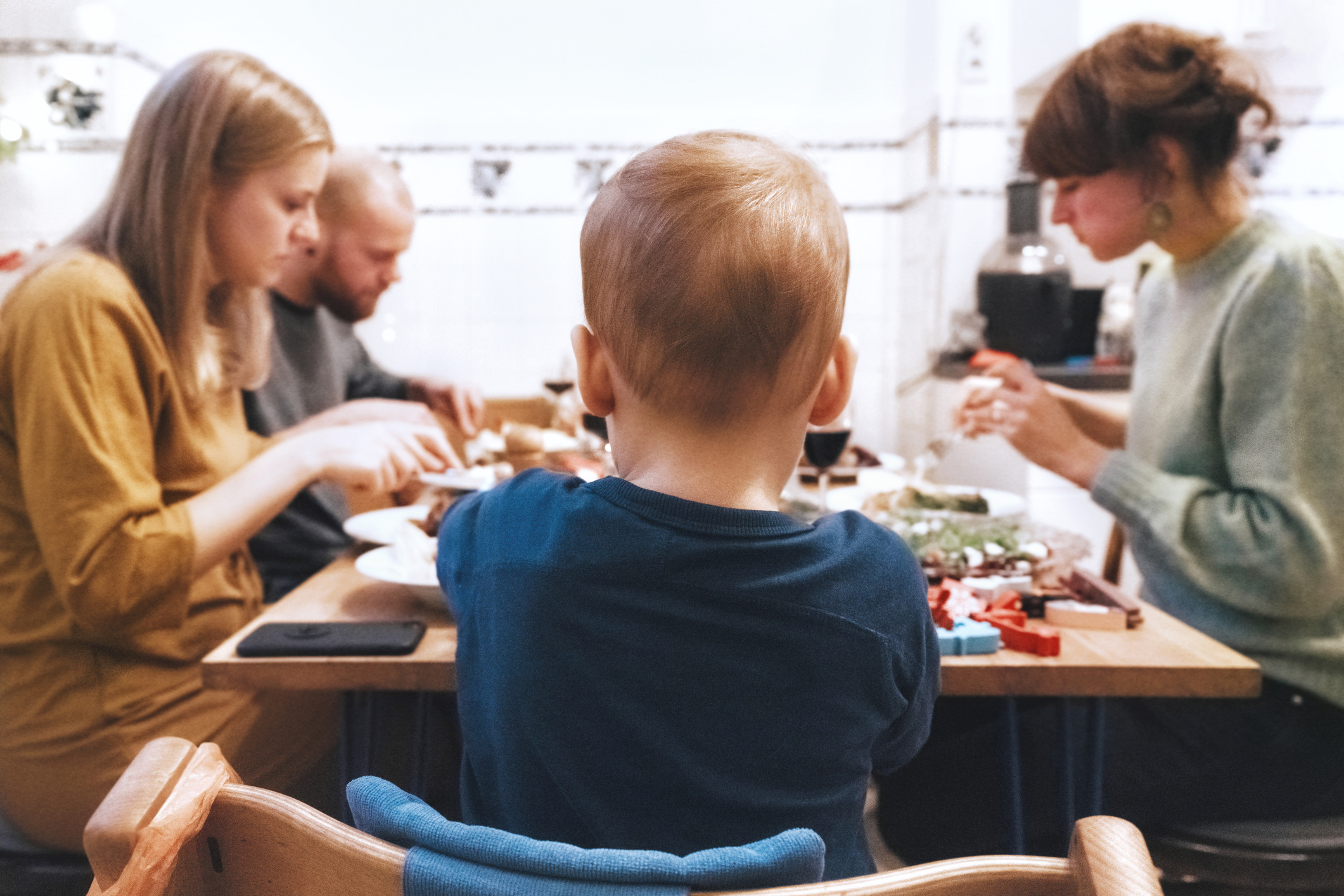Drei Erwachsene und ein Baby sitzen an einem Tisch und essen.