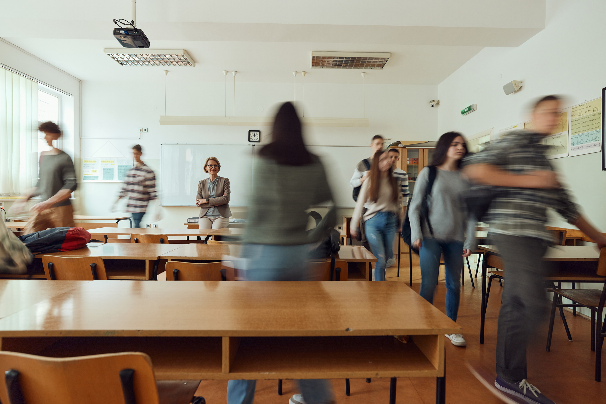Ein Klassenzimmer mit Schülerinnen und Schülern, die zu ihren Plätzen gehen.