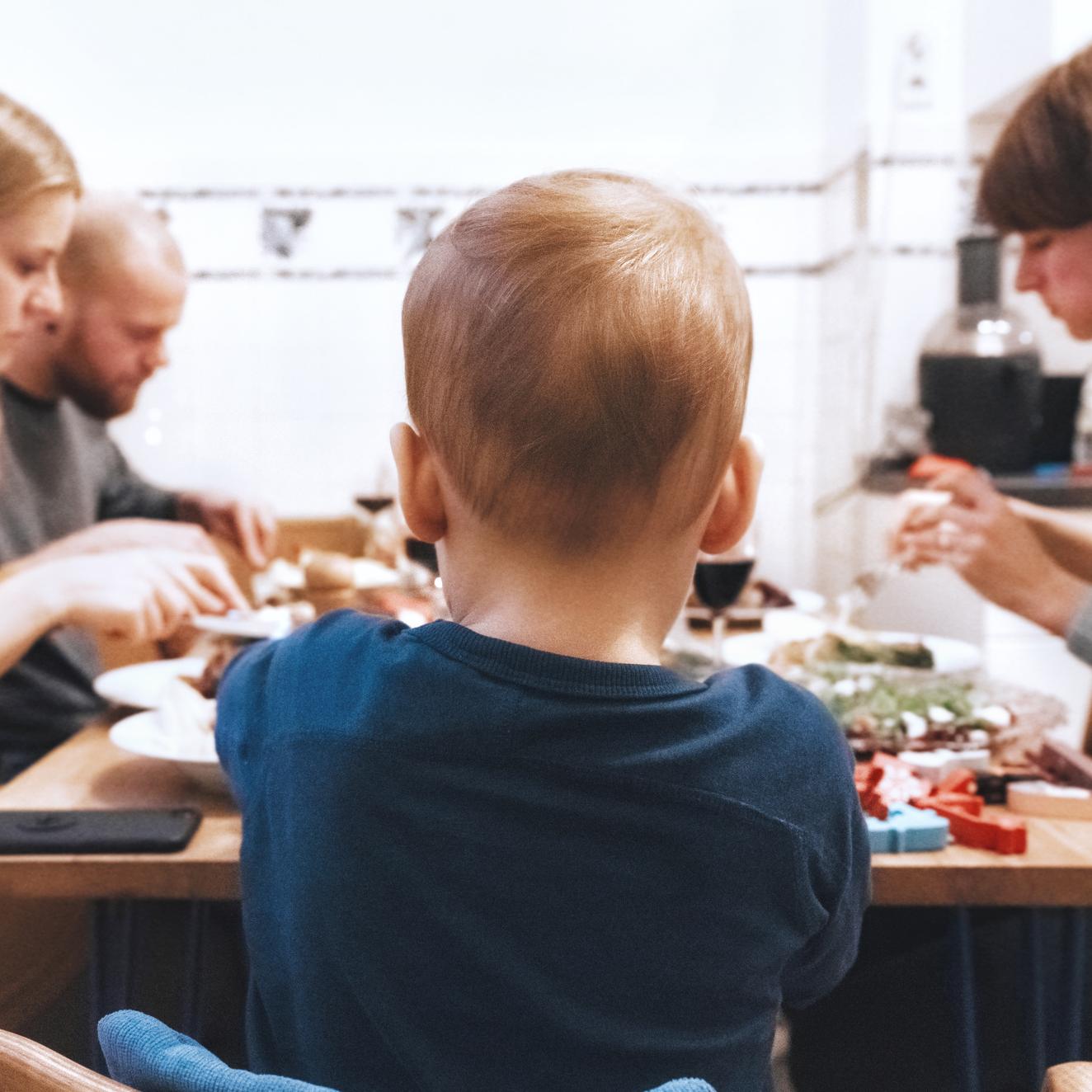 Drei Erwachsene und ein Baby sitzen an einem Tisch und essen.